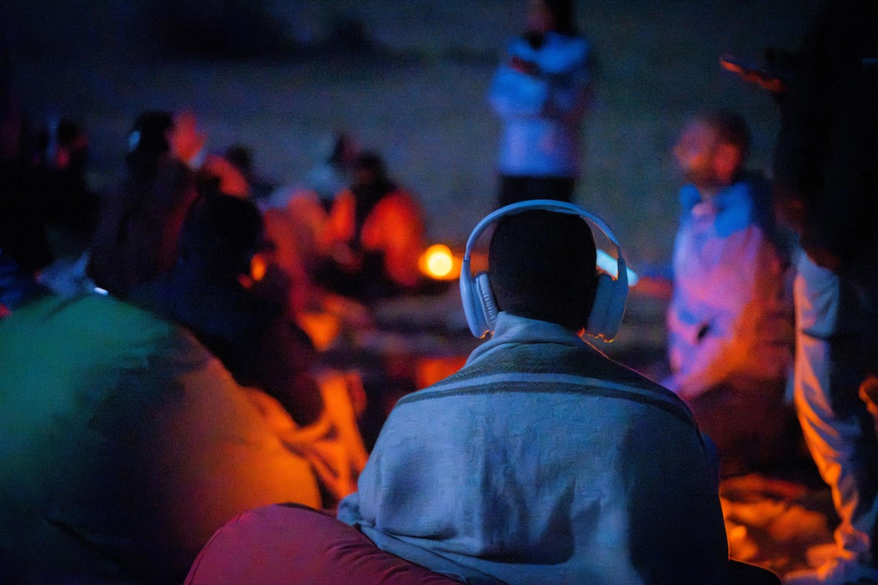 Mansour wearing headphones during a stargazing session at night, using interactive audio and tactile tools to navigate the night sky at Six Senses Southern Dunes