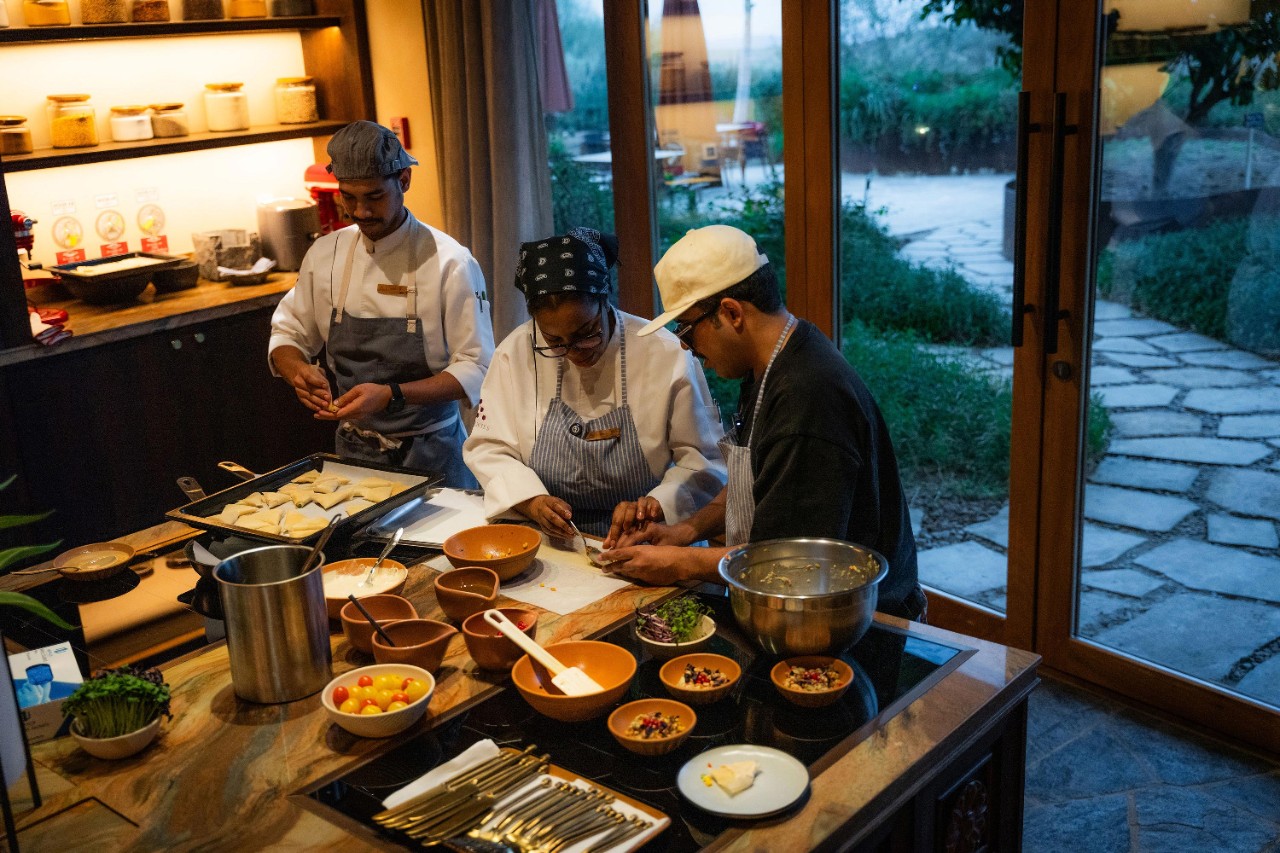 Chef Afnan Alhawasawi leading a cooking class at Six Senses Southern Dunes, with Abdulaziz and Afnan rolling samosas